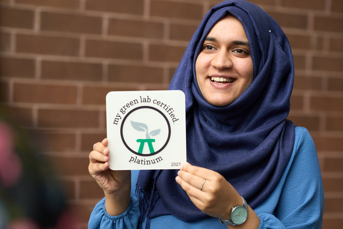 woman wearing hijab holding a plaque with my green lab certification platinum status