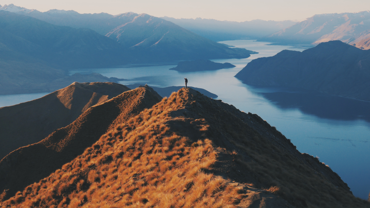 Inspiring image of a person on top of a mountain in the middle of a fjord